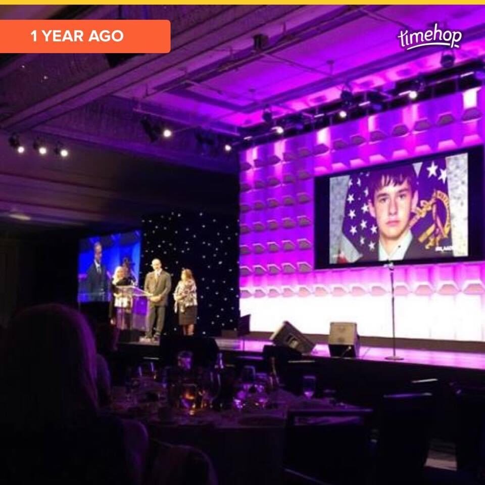 Tina speaking on stage with Tyler's photo on screen
