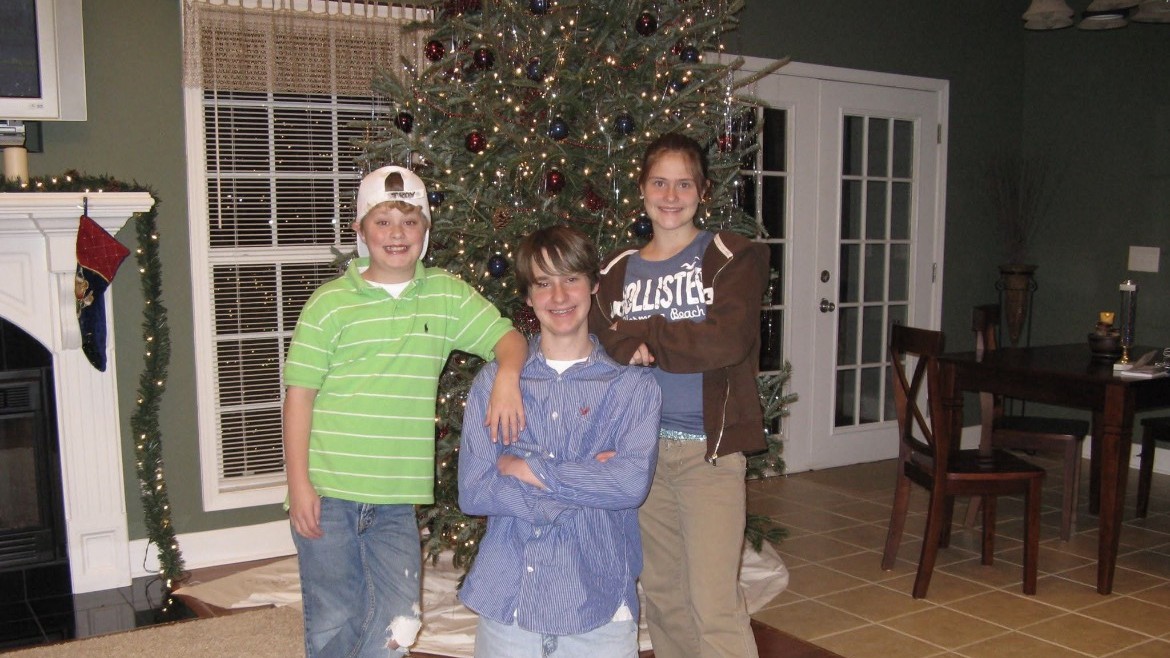 Tyler with his brother and sister by the Christmas tree